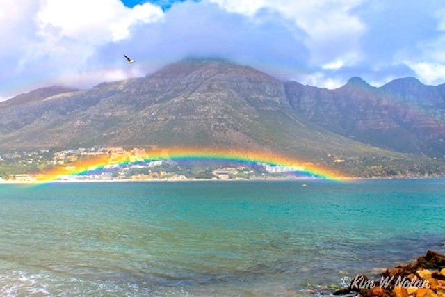 Photograph of a rainbow over the ocean in Cape Town, South Africa by Kim W. Nolan